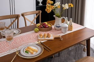Macro detail of geometric chevron table runner with decorative cotton tassels