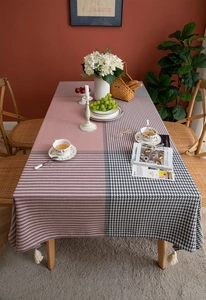 Detail of jacquard tablecloth featuring pink stripes, houndstooth patterns and white tassels
