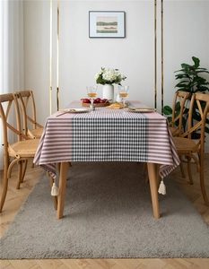 Detail of pink striped and checkered tablecloth featuring decorative cream tassels