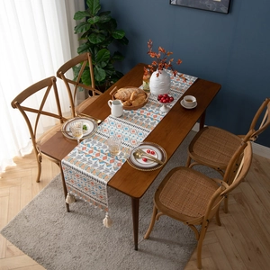 Detail showing bohemian geometric patterned table runner with white cotton tassels