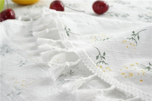 Macro shot of cotton daisy tablecloth featuring crochet lace edges and white tassel trim