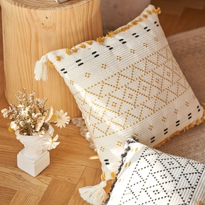 Dettaglio della federa boho in cotone lavorato a maglia con nappe e motivi geometrici