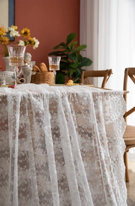 Détail d'une nappe en dentelle blanche avec broderies florales et bordures festonnées