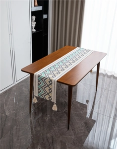 Dettaglio di runner da tavola geometrico colorato con nappine in cotone color crema