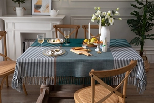 Detail of green houndstooth tablecloth with decorative tassel edges on a wooden table