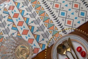 Detail of colorful geometric boho table runner with cotton tassels on a dark wood table