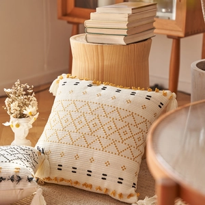 Dettaglio della federa boho in maglia con nappe gialle e motivi geometrici trapuntati