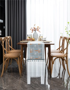 Detail of modern geometric chenille table runner with colorful pom-poms and tassels