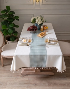 Detail of green houndstooth pattern and delicate fringe tassels on the white tablecloth