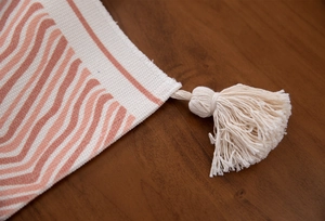 Detail view of bohemian cotton table runner with woven tassels and red wave patterns