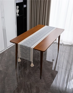 Close-up of geometric wave pattern cotton table runner with handmade tassels on wooden table
