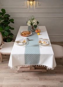 Close-up of cream rectangular tablecloth with green geometric jacquard and fringe edges