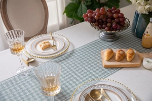 Detailed view of green houndstooth table runner with elegant fringe and woven texture