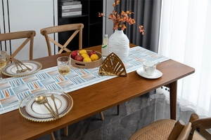 Modern geometric table runner with blue and orange triangles on a dark wood dining table