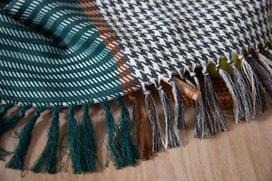 Close-up of thick houndstooth pattern fabric with decorative fringe on wooden table