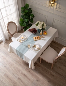 Detail of cream rectangular tablecloth with green houndstooth pattern and tassel trim