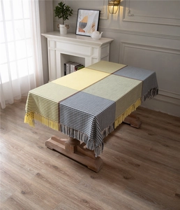 Detail of modern houndstooth tablecloth with yellow and gray panels and fringe tassels