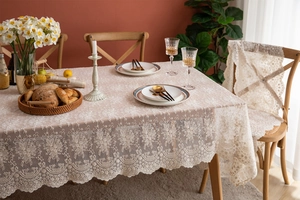 Détail de nappe rectangulaire en dentelle blanche avec broderies et bordures festonnées