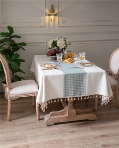 Detail of cream tablecloth with sage green houndstooth pattern and tassel fringe