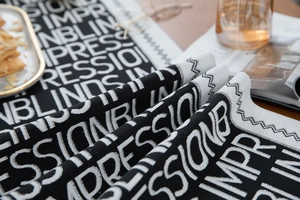 Detailed texture of black and white jacquard table runner with bold typography on wood table