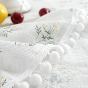 Floral cotton tablecloth with green botanical prints and white pom-pom fringe details