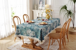 Detail of vintage floral jacquard tablecloth with elegant off-white cotton tassels