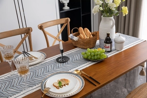 Close-up of blue and white geometric zigzag table runner with decorative cotton tassels