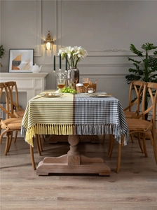 Detail of modern houndstooth and yellow patterned tablecloth with fringe tassels