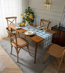 Detailed view of modern blue checkered table runner with elegant pompom fringe on a wood table