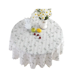 Pastel floral cotton round tablecloth with white pom-pom fringe in a rustic garden style