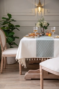 Detailed texture of jacquard tablecloth with geometric patterns and white fringe edges