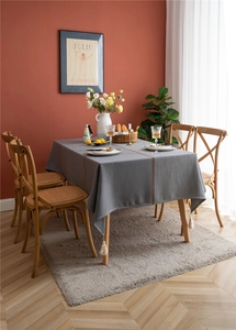 Detail of grey and houndstooth jacquard tablecloth with tassels on a wooden table