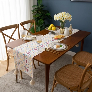 Modern geometric colorful table runner with boho tassels on a dark wood dining table
