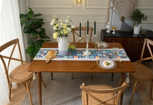 Vue détaillée du chemin de table bleu à motifs de poissons avec pompons en coton blanc