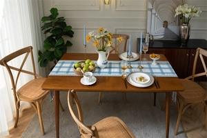 Blue and white plaid table runner detail with handcrafted tassels on a wooden dining table