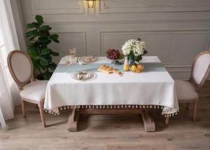 Detail of white jacquard tablecloth with houndstooth pattern and delicate fringe edge