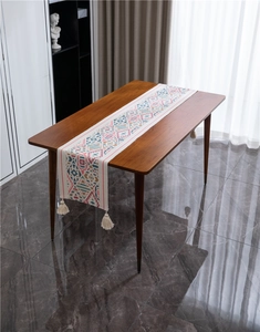 Dettaglio di runner da tavolo boho geometrico colorato con nappe in cotone su legno
