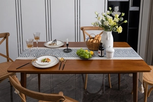 Close-up of blue and white zigzag table runner with tassels on a dark wood dining table