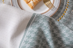Detailed close-up of sage green houndstooth pattern and cream rhombus jacquard tablecloth