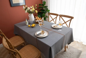 Detail of grey houndstooth tablecloth with brown stripe and decorative white tassels