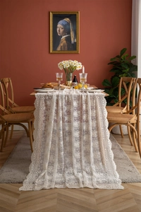 Détail d'une nappe en dentelle française blanche avec broderie florale et bords ondulés