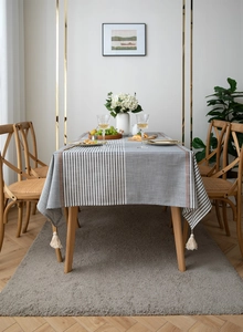 Detail of grey and white striped polyester tablecloth with rustic orange accents and tassels