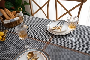 Detail of woven houndstooth tablecloth with orange stripes in an elegant dining setting