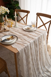 Gros plan sur la nappe en dentelle ivoire avec broderies raffinées et bordure ondulée