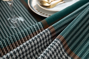 Detailed texture of woven houndstooth tablecloth with green, white and brown yarns