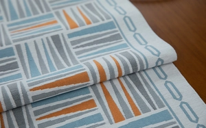 Close-up of geometric chenille table runner with orange and blue triangle patterns