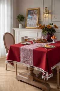 Detalle de mantel vintage rojo con motivos florales de jacquard y bordes de flecos