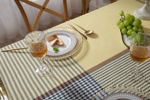 Detail of thickened houndstooth and geometric patchwork tablecloth on an elegant dining table