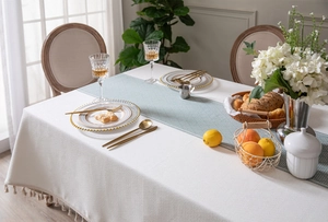 Macro detail of cream jacquard tablecloth with textured weave and fringe tassels