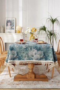 Detail of vintage blue floral jacquard tablecloth with elegant cream fringe tassels